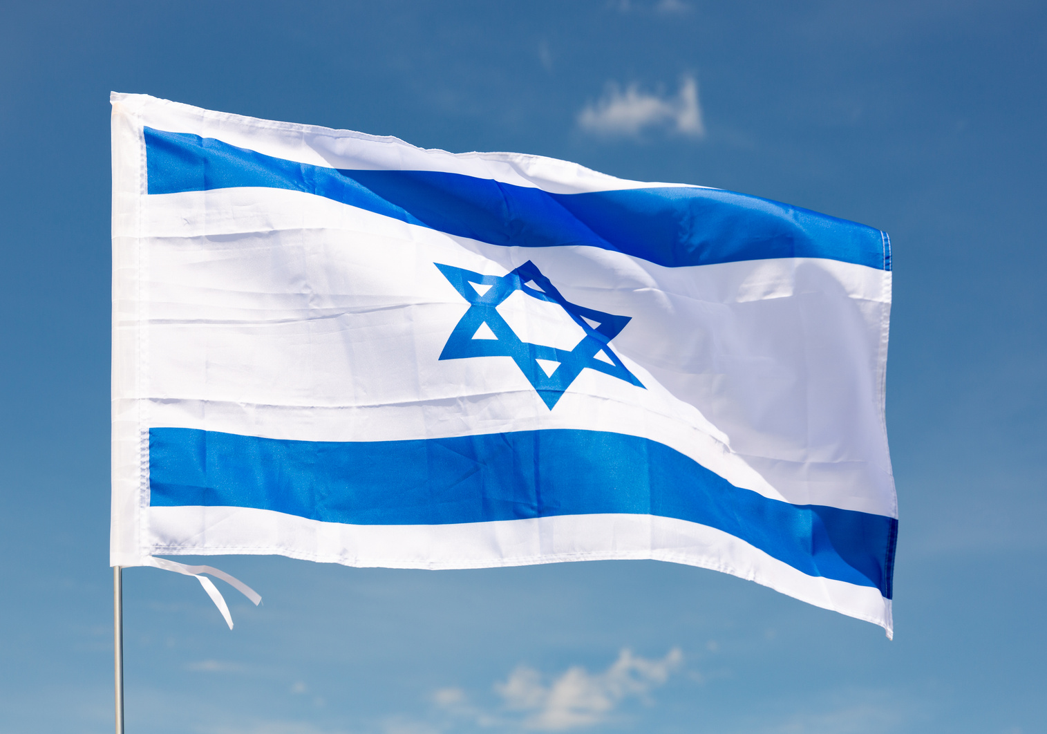 Flag of Israel waving on cloudy sky during daytime